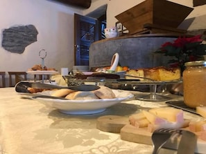 A breakfast buffet with various breads, pastries, and a fruit display. - Le Moulin des Aravis (Pontboset)
