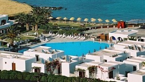 A resort with a swimming pool, beach umbrellas, and a sailboat on the water. - Porto Paros (Paros)