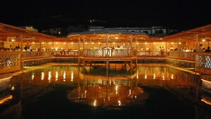 A covered outdoor area with a pool, wooden structures, and people. - Porto Paros (Paros)