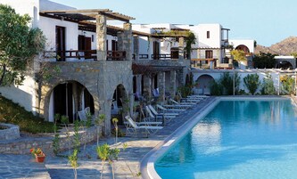 Zona junto a la piscina con sillas de descanso y un edificio de piedra con arcos.