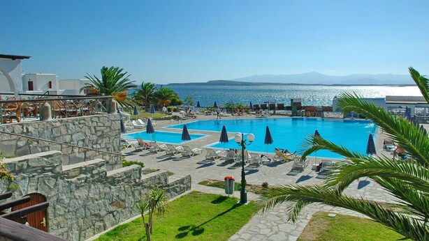 A resort pool area with multiple swimming pools, lounge chairs, and umbrellas. - Porto Paros (Paros)