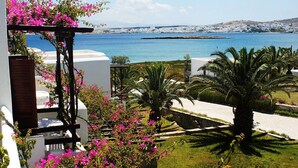 A coastal view with white buildings, a clear blue sea, and pink bougainvillea flowers. - Porto Paros (Paros)