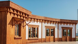 Ein Holzgebäude mit großen Fenstern und Türen, einem überdachten Gang und einem Fliesenboden.