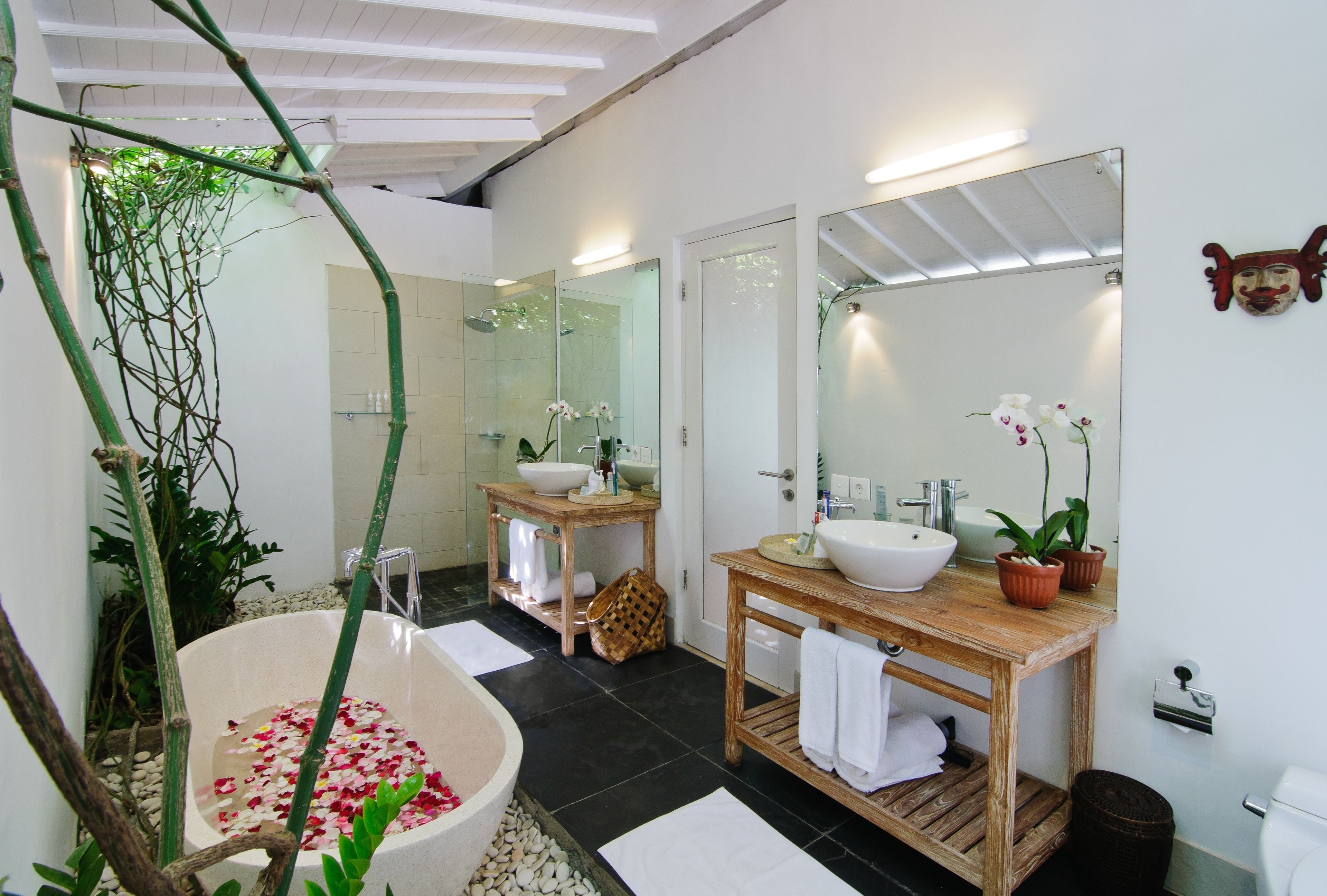A modern bathroom with a large bathtub, two sinks, and a wooden vanity.