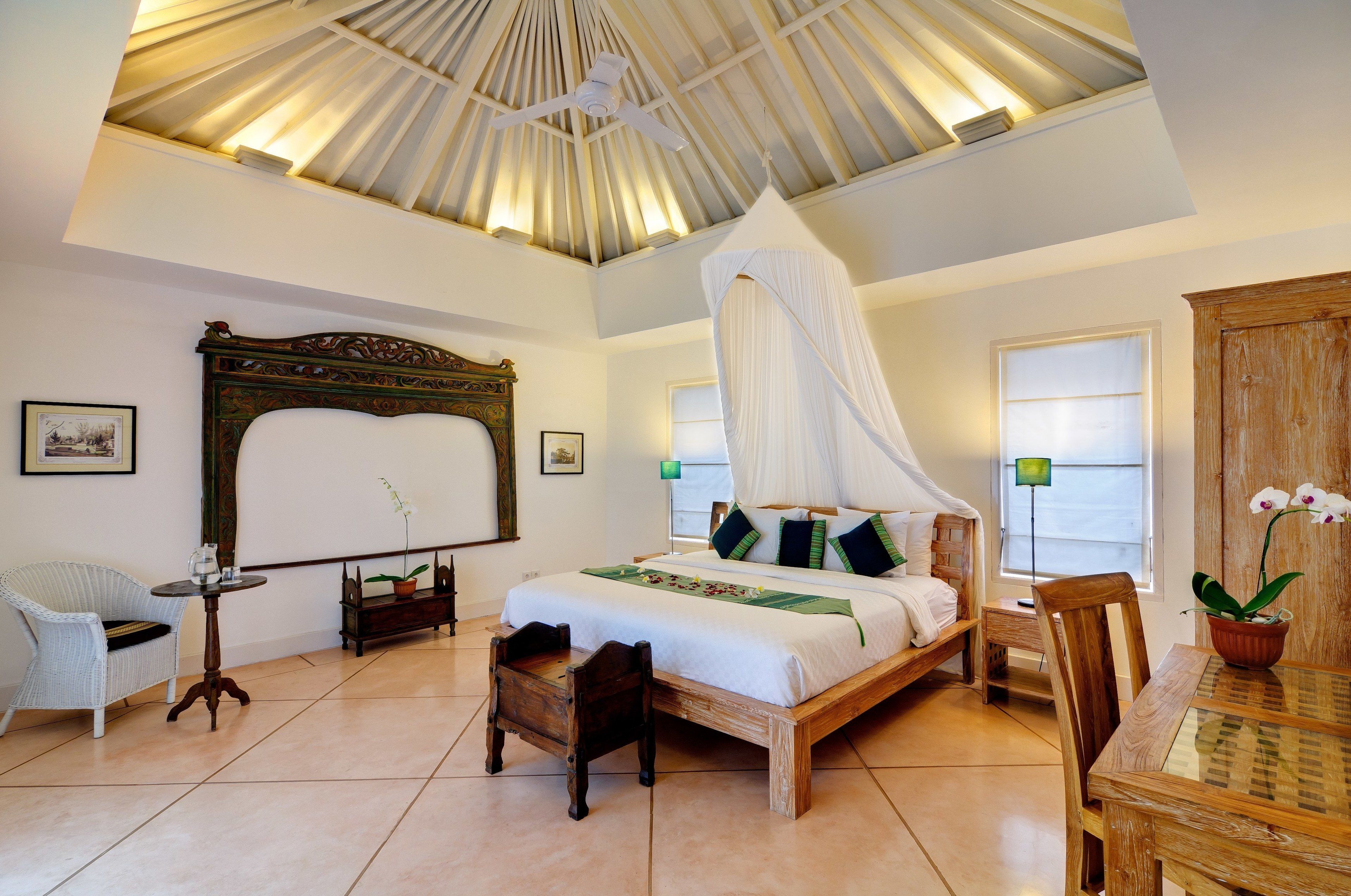 A spacious bedroom with a large bed, a wooden headboard, a canopy bed, a wooden table, and a chair.