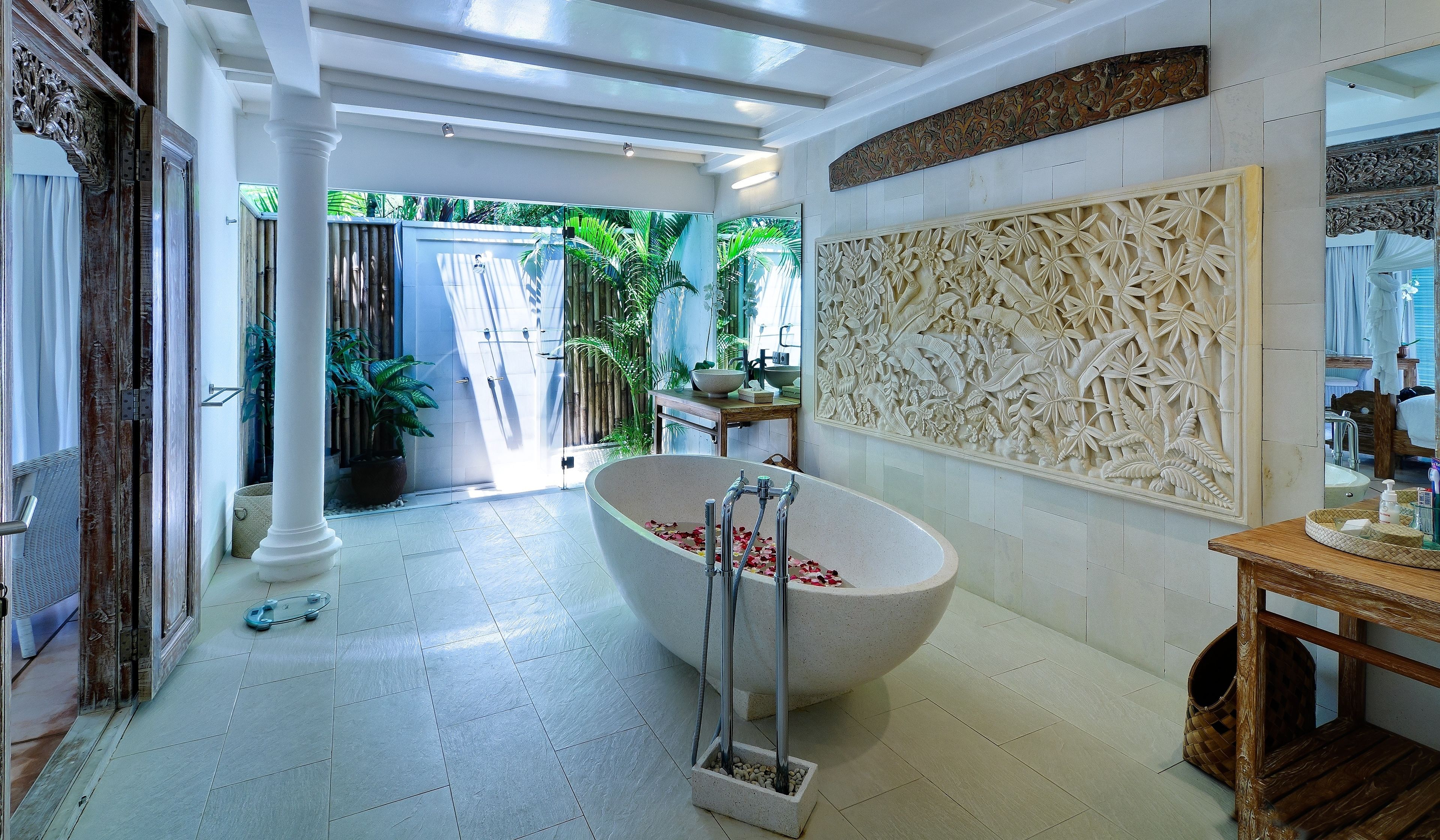 Un baño amplio con una bañera independiente, un espejo grande y un panel decorativo en la pared.
