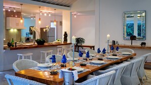 Comedor con una larga mesa de madera dispuesta para una comida, rodeado de sillas de mimbre.
