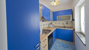 A kitchen with blue cabinets, a gas stove, a sink, and a decorative ceiling light. - Casa Agata (Praiano)