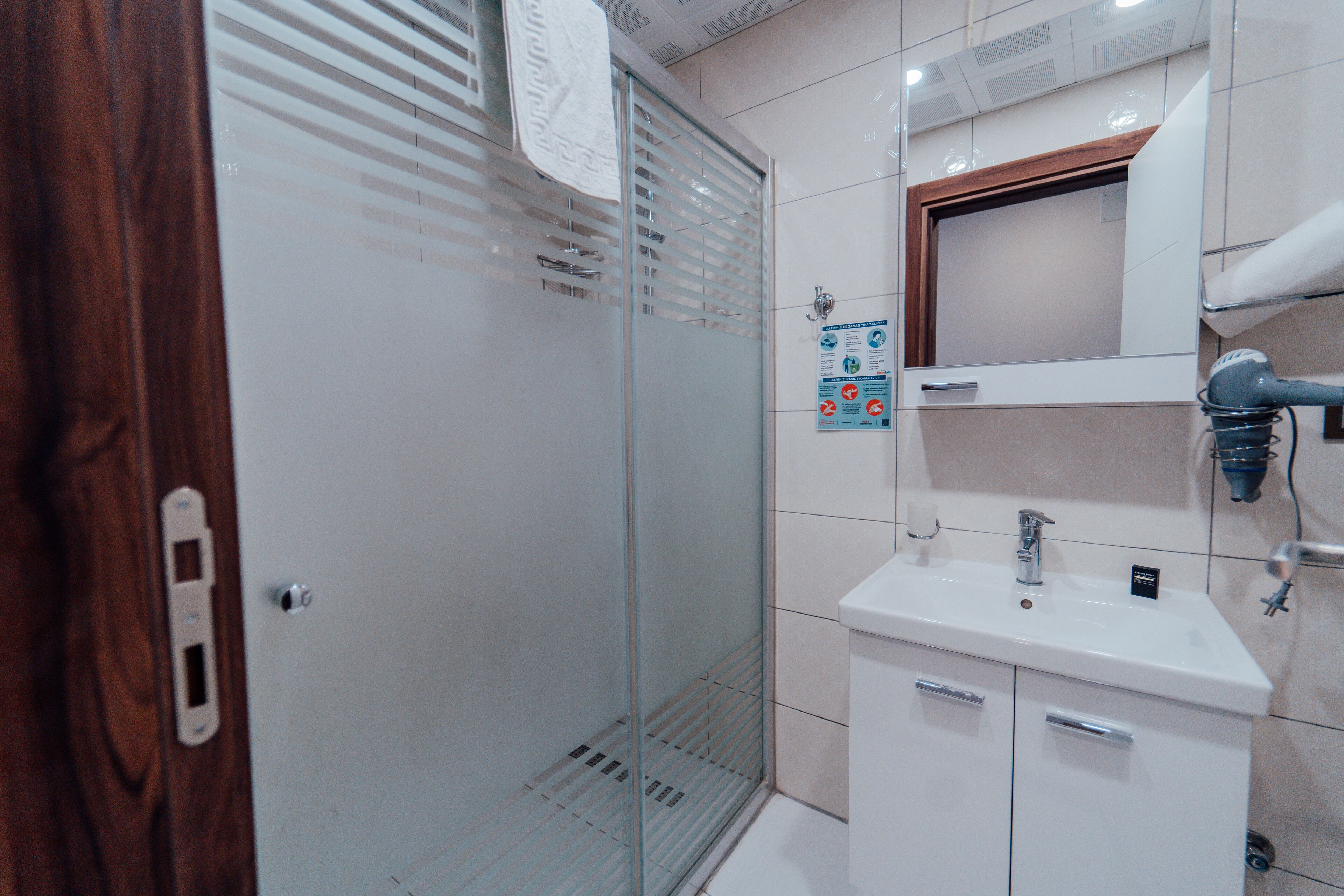 Un baño moderno con cabina de ducha de vidrio, un lavabo blanco y un espejo encima.