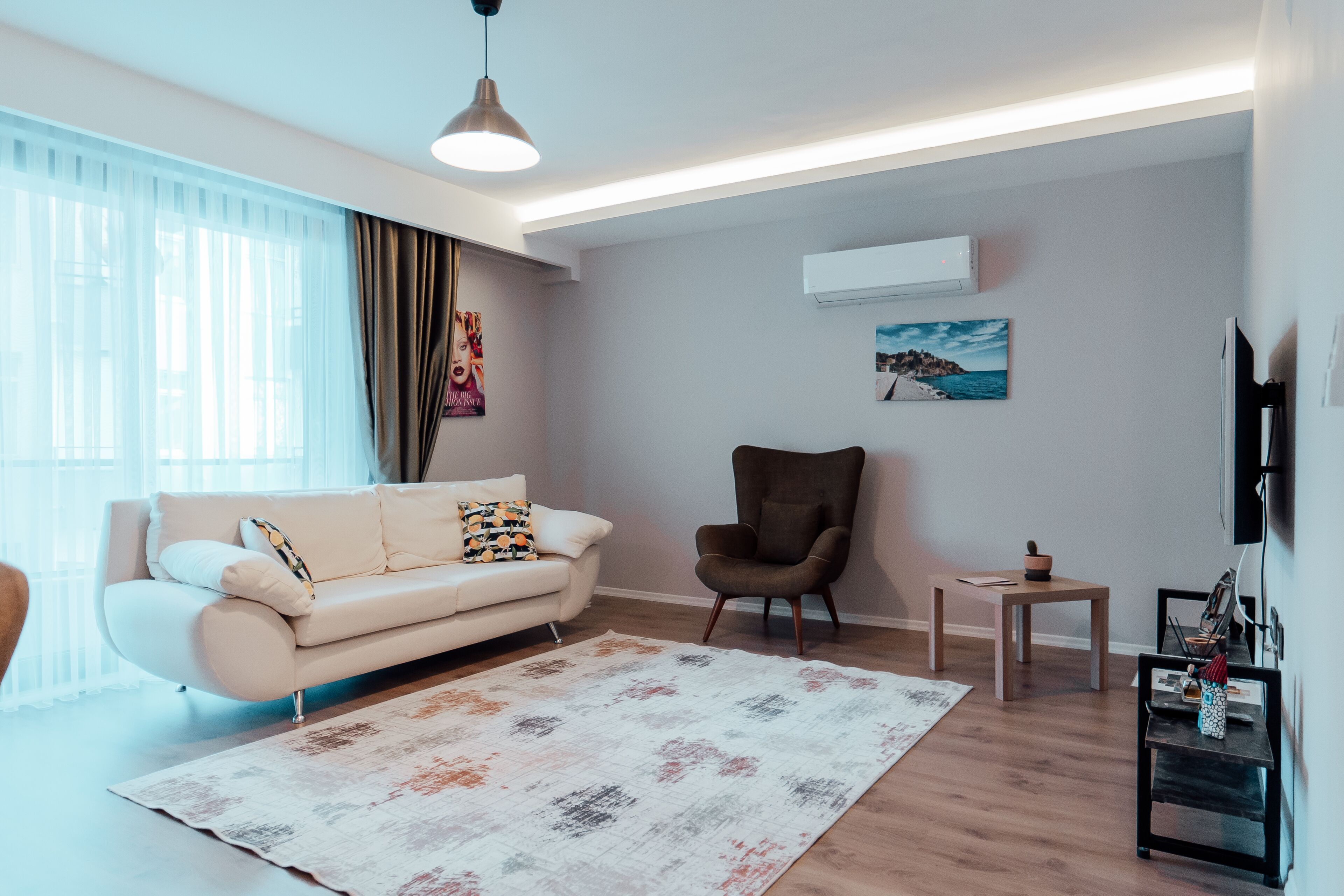 Una sala de estar moderna con sofá, sillón y televisor de pantalla plana.