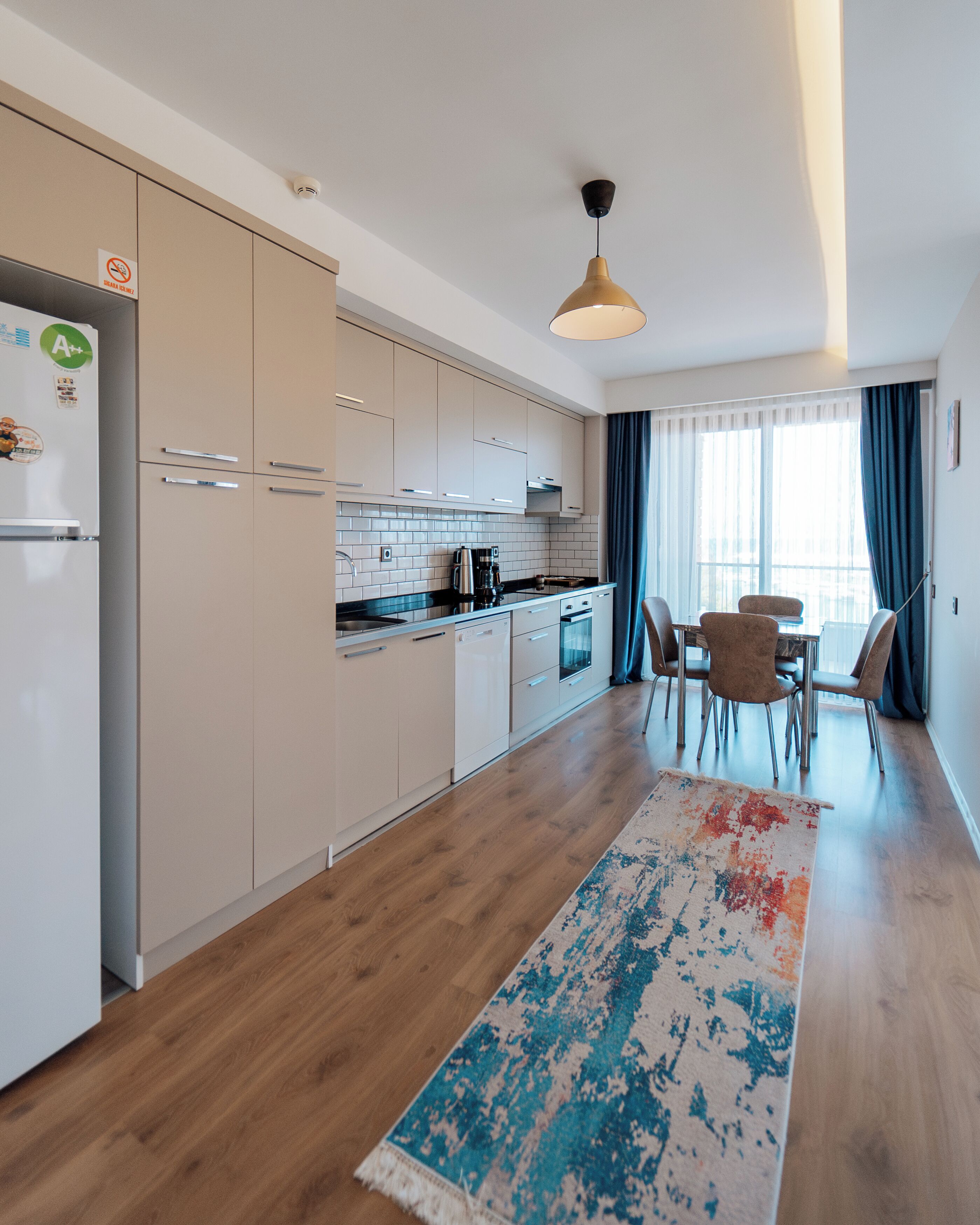 A modern kitchen with white cabinets, a coffee machine, and a dining area with a table and chairs.