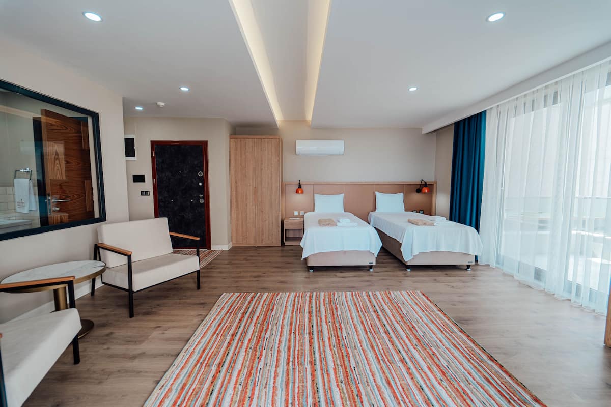 Une chambre d’hôtel moderne avec deux lits, un canapé, une petite table et un grand miroir.