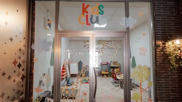 Kids Club entrance features a colorful play area with toys and furniture, visible through a glass door.