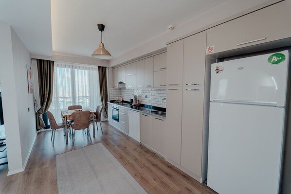 Una cocina moderna con armarios blancos, un refrigerador de acero inoxidable y un comedor con mesa y sillas.