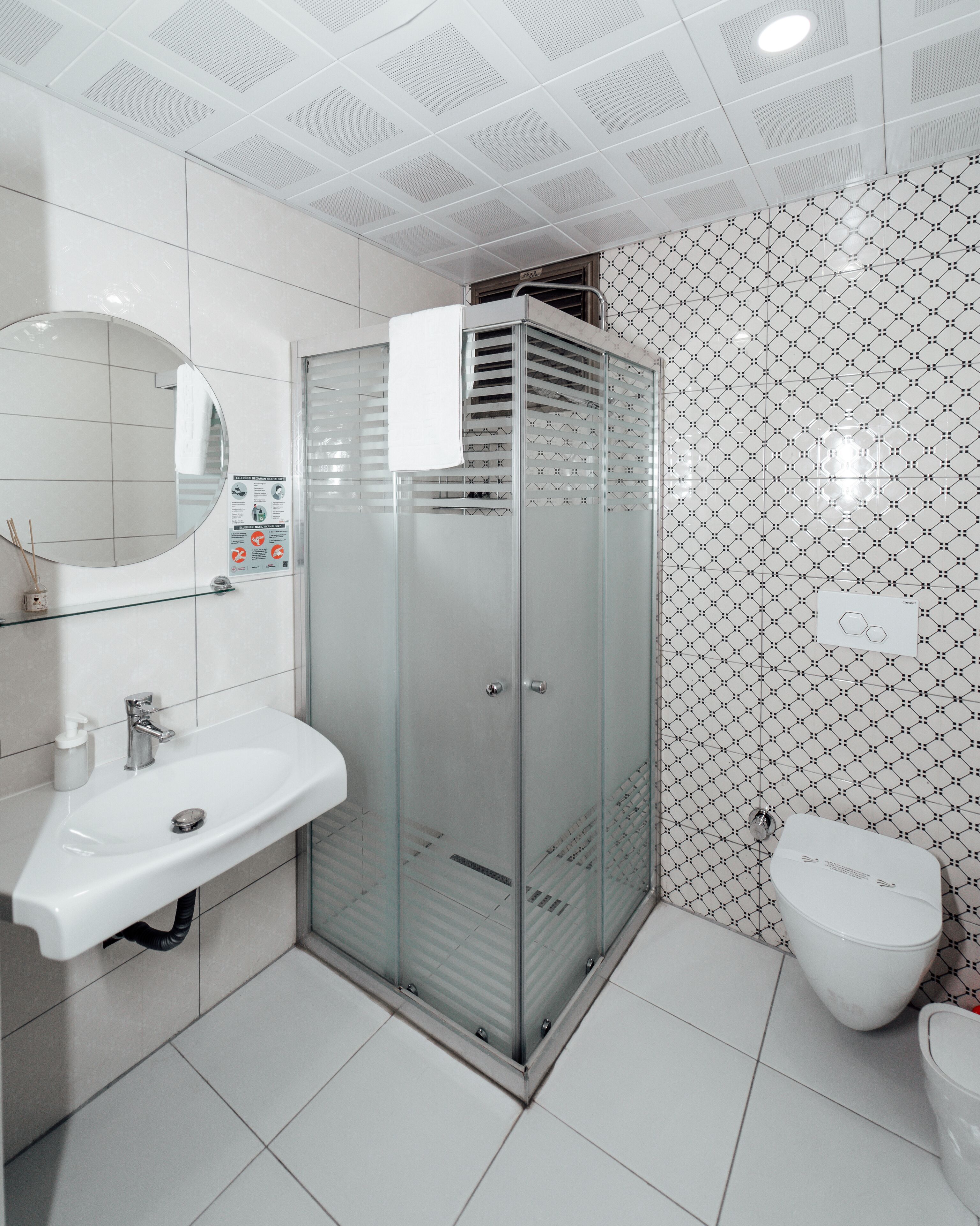 A modern bathroom with a glass-enclosed shower, a white sink, and a toilet.