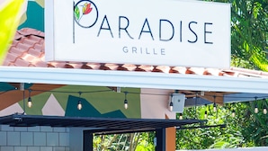 A restaurant named 'Paradise Grille' with outdoor seating and a tiled patio. - Bird of Paradise Hotel (Jacó)
