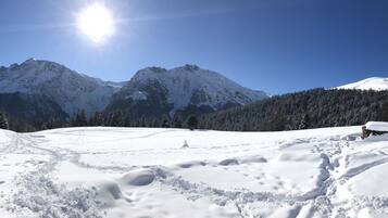 Un paisaje montañoso nevado con cielos despejados y un sol brillante.