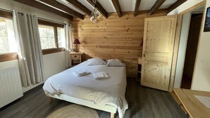 Un dormitorio con paneles de madera, una cama, mesitas de noche y una lámpara.