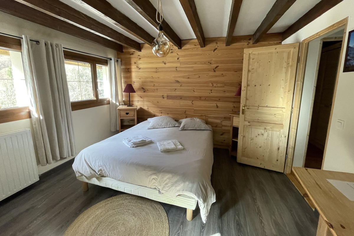 Ett sovrum med träpanel på väggarna, en säng, sängbord och en lampa.
