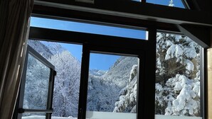 Una habitación con amplios ventanales con vistas a un paisaje montañoso nevado.