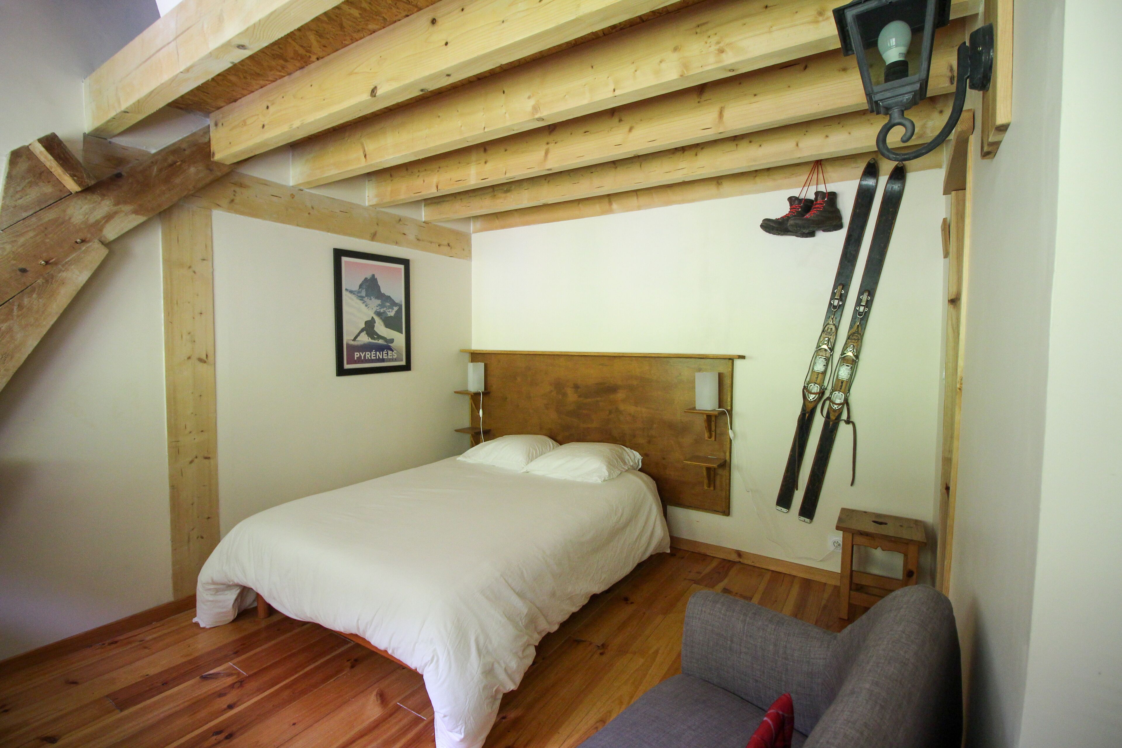 Une chambre avec un plafond en bois, un lit, une table de chevet, une chaise et une paire de skis accrochés au mur.