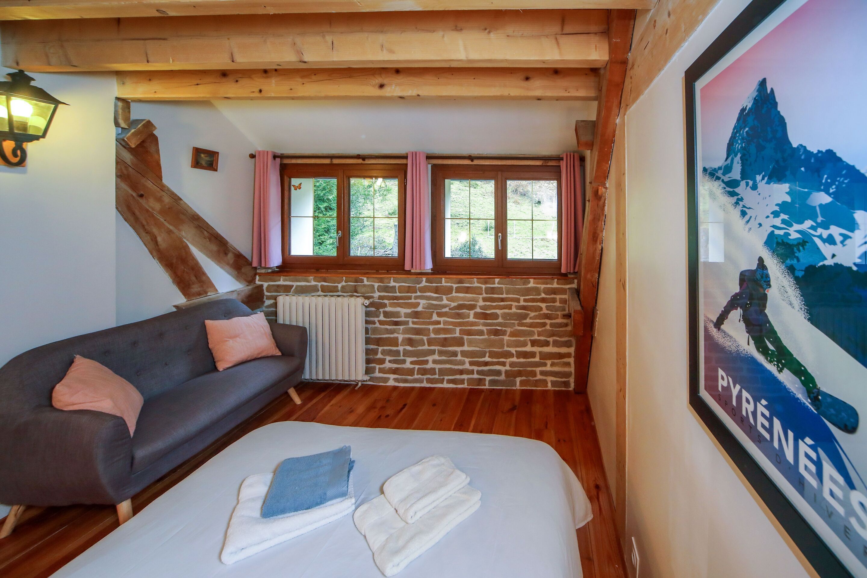 Una habitación acogedora con cama, sofá, pared de piedra y ventana con cortinas.