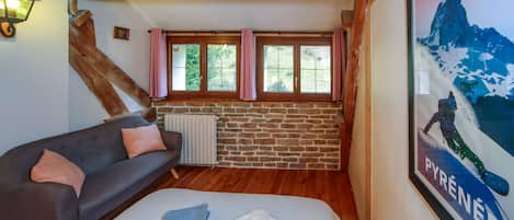 Ein gemütliches Zimmer mit einem Bett, einer Couch, einer Steinwand und einem Vorhangfenster.