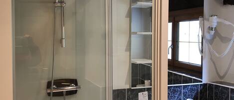 A modern bathroom with a glass-enclosed shower, a white sink, and a hairdryer mounted on the wall.