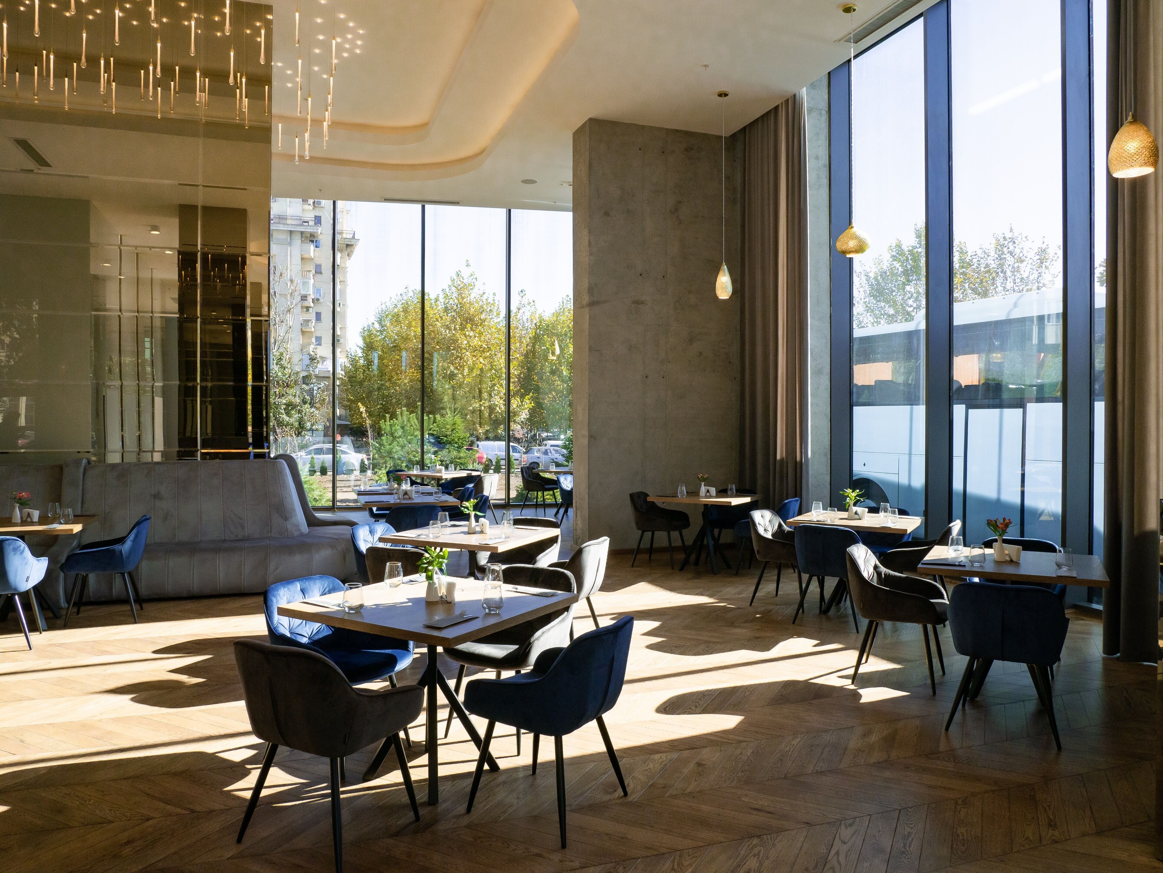 Un espace de restauration moderne doté de grandes fenêtres, d’un plancher en bois et de meubles contemporains.