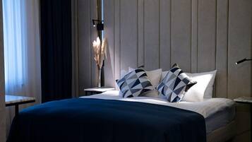 A hotel room with a bed, a nightstand, a lamp, and a window with curtains.