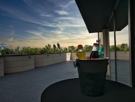 A rooftop terrace with a black metal table holding bottles and a drink.