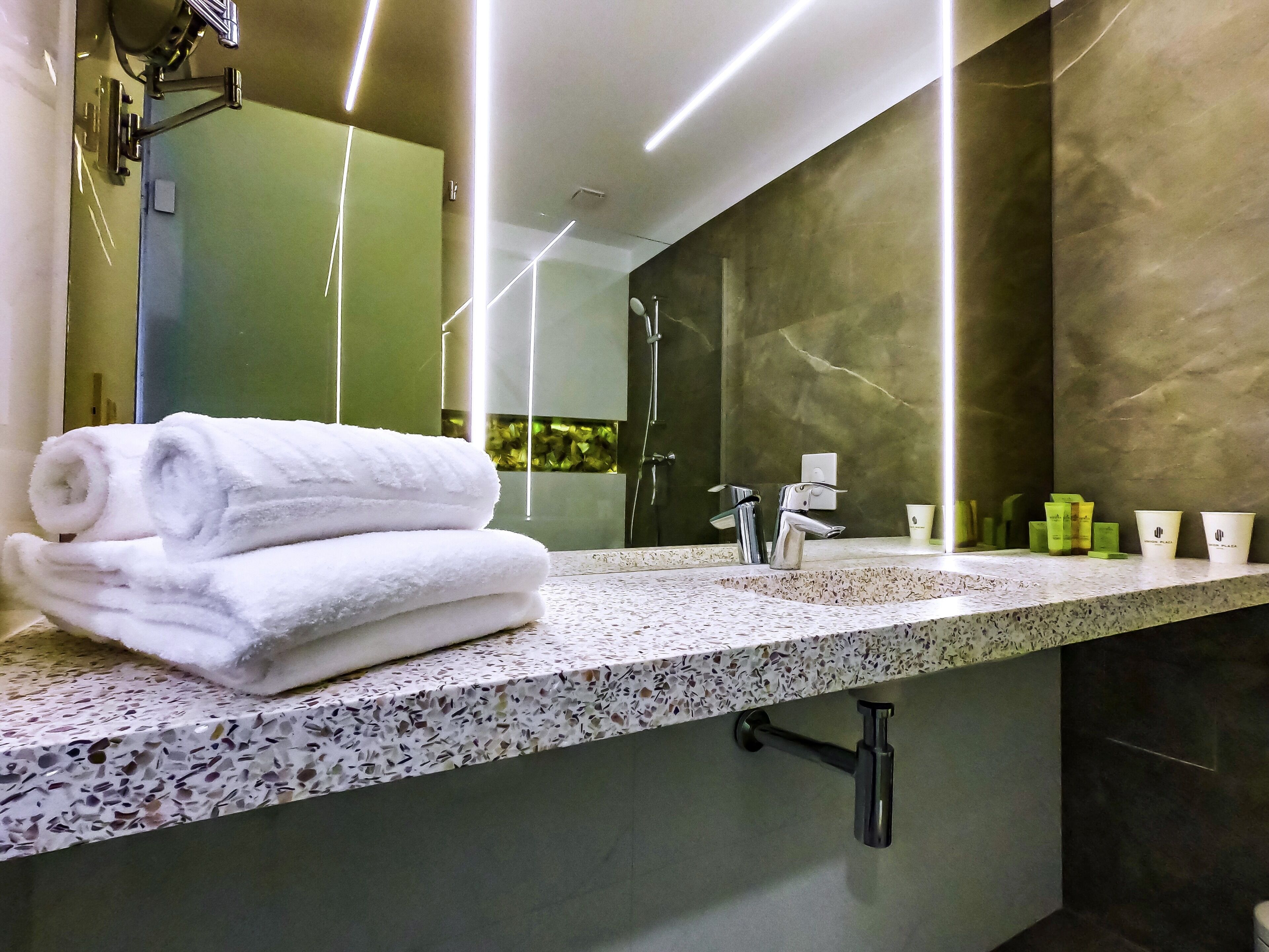 Een moderne badkamer met een marmeren aanrechtblad, een grote spiegel en een handdoekrek.