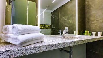 Een moderne badkamer met een marmeren aanrechtblad, een grote spiegel en een handdoekrek.