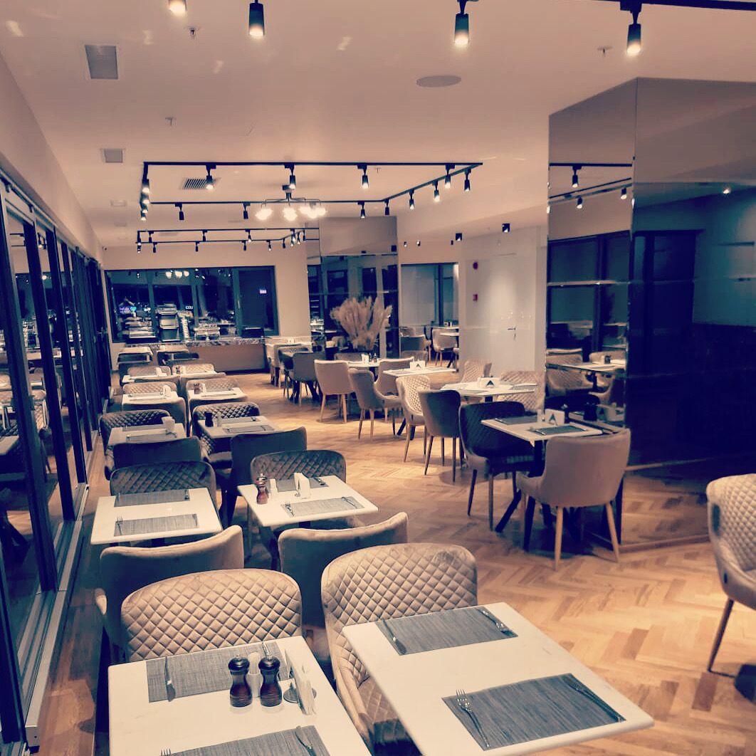 En moderne restaurant med flere spiseborde og stole, indrettet med god plads.