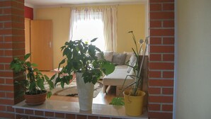 A living room with a sofa, a coffee table, and several potted plants. - Cozy apartment in Rostock with WiFi (Rostock)