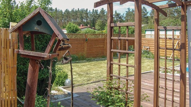 A wooden deck with a birdhouse and a wooden pergola. - Cozy apartment in Rostock with WiFi (Rostock)