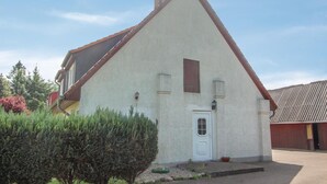 A single-story house with a steeply pitched roof, a white exterior, and a small front porch. - Cozy apartment in Rostock with WiFi (Rostock)