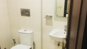A small, clean bathroom with a toilet, a sink, and a mirror. - Hotel Gaylord (New Delhi)