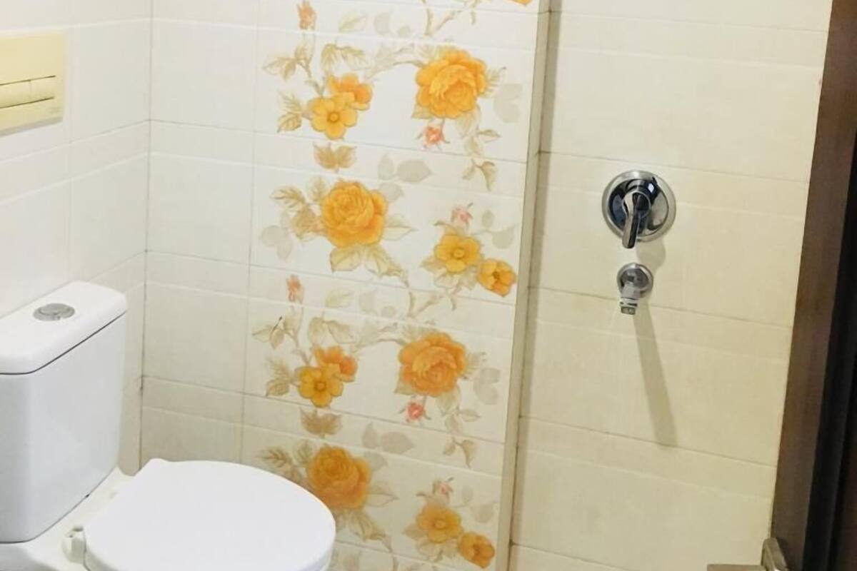 A bathroom with a toilet, a shower with a glass door, and a wall with floral tiles.