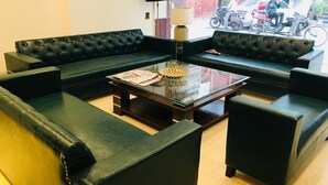 A lobby with a sofa set, a glass coffee table, and a lamp. - Hotel Gaylord (New Delhi)