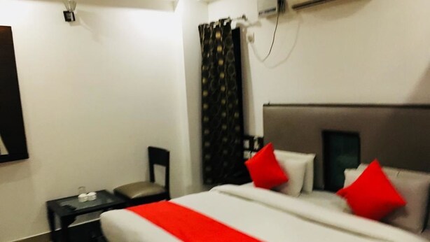 A hotel room with a large bed, two bedside tables, a nightstand, a headboard, and a window with curtains. - Hotel Gaylord (New Delhi)
