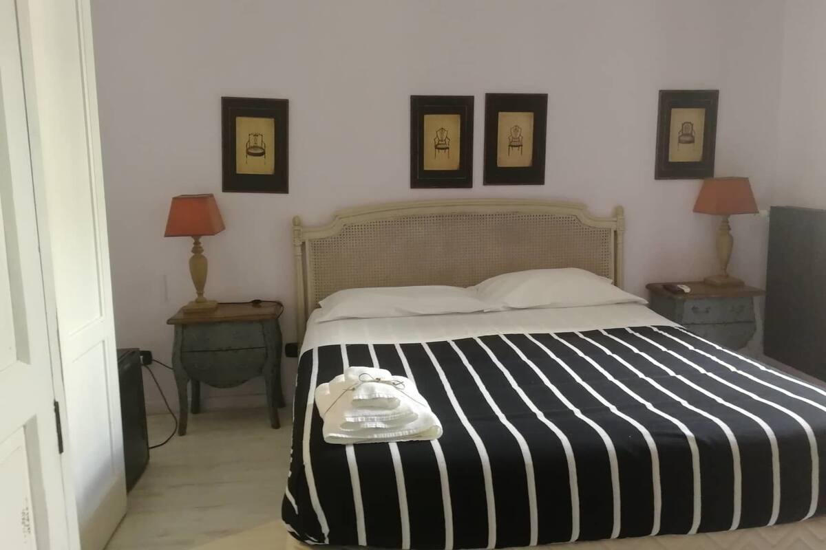 A hotel room with a bed, two bedside tables with lamps, and three framed pictures on the wall.