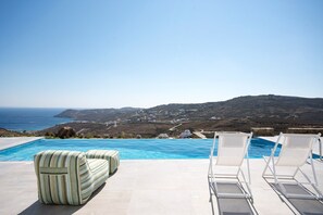 Zona junto a la piscina con vista al mar y a las colinas.