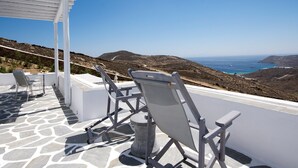 A terrace with white chairs and a pergola overlooking a coastal landscape. - Chrysanthemo Villas (Mykonos)
