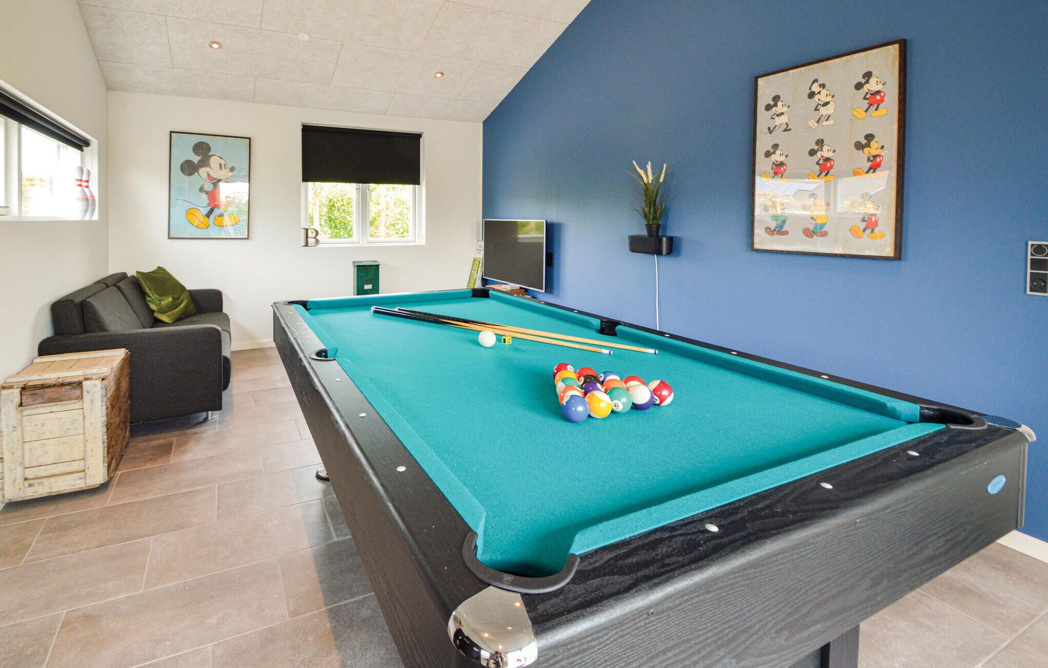 A pool table with balls, a sofa, a small table, and a framed picture on the wall.