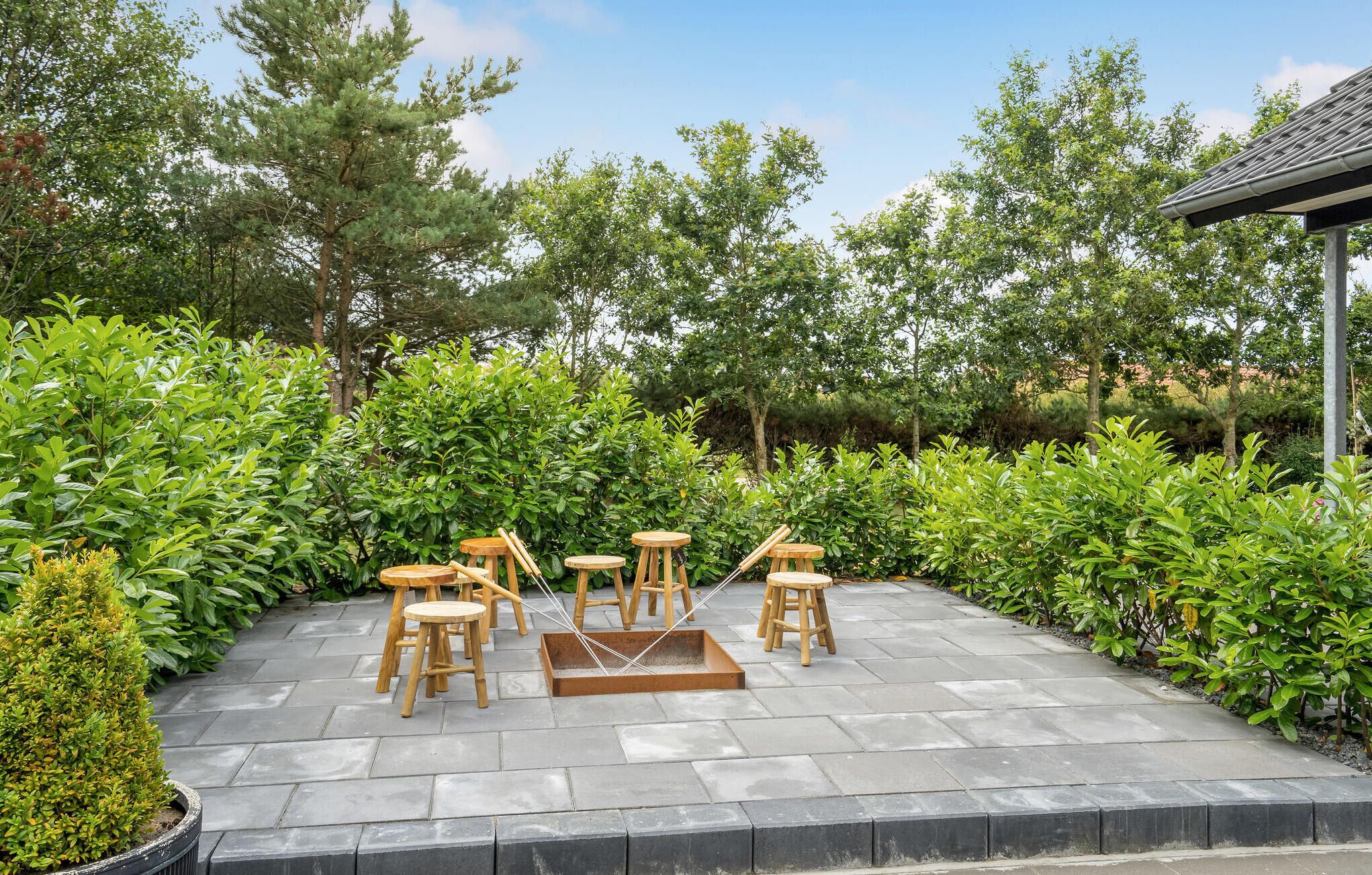 An outdoor patio with stone flooring, surrounded by lush greenery and trees.