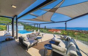 Eine großzügige Außenterrasse mit Pool, Sitzgelegenheit und Blick auf das Meer und die Stadt.