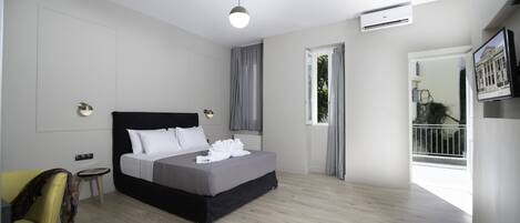 A modern bedroom with a large bed, a small side table, a chair, and a window with curtains.