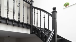 A curved staircase with dark wooden balusters and a black handrail, leading to an upper floor. - Plaka Arch Suites (Athens)