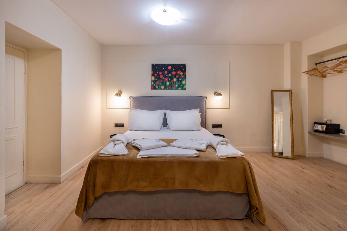 Une chambre d’hôtel bien rangée, avec un lit, un tableau accroché au mur et un miroir.